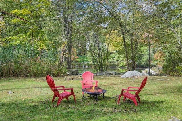 view of yard with an outdoor fire pit and a wooded view