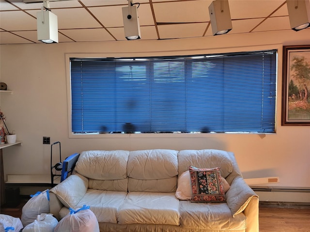 interior space featuring a paneled ceiling, baseboards, baseboard heating, and wood finished floors