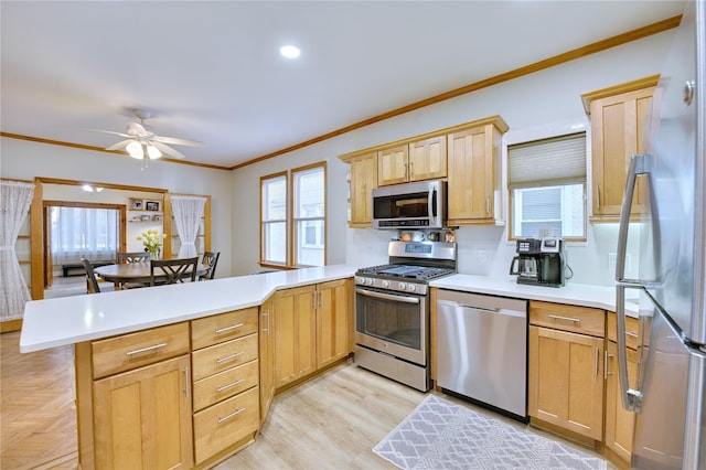 kitchen with crown molding, stainless steel appliances, light countertops, light brown cabinets, and a peninsula