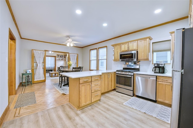 kitchen with ornamental molding, appliances with stainless steel finishes, a peninsula, light countertops, and light brown cabinetry