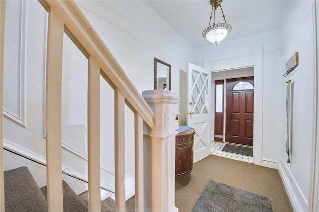 foyer entrance featuring dark carpet and stairway