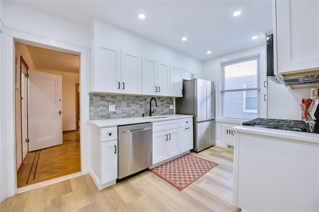 kitchen with appliances with stainless steel finishes, light countertops, a sink, and white cabinetry