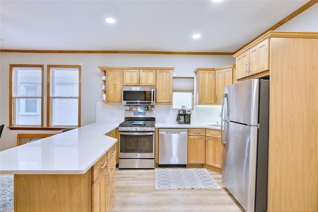 kitchen featuring light wood finished floors, a peninsula, stainless steel appliances, light countertops, and light brown cabinets