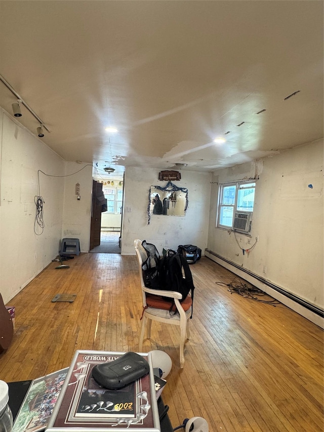 interior space featuring track lighting, wood-type flooring, and a baseboard radiator