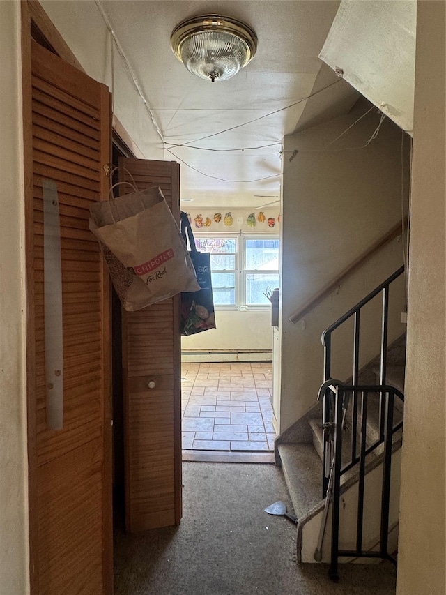 hallway featuring stairs and a baseboard heating unit