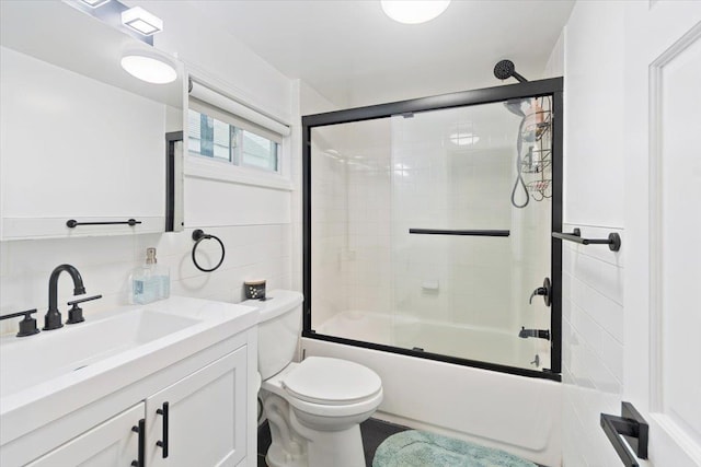 full bathroom featuring toilet, bath / shower combo with glass door, and vanity