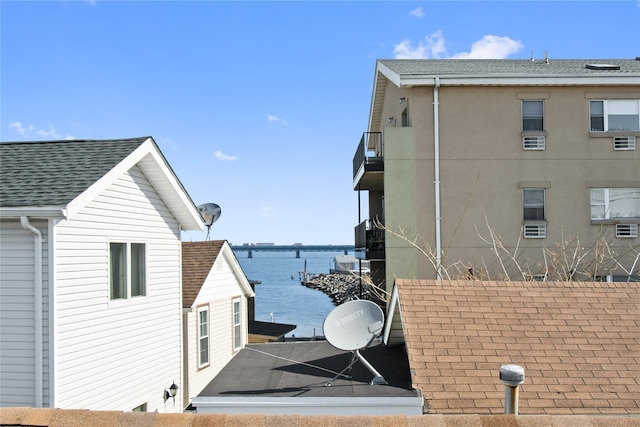 view of property exterior featuring a shingled roof and a water view