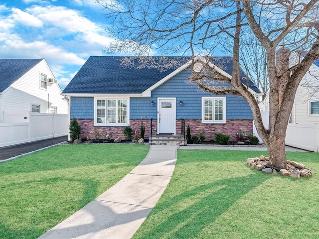 view of front of house featuring fence, a front lawn, and roof with shingles