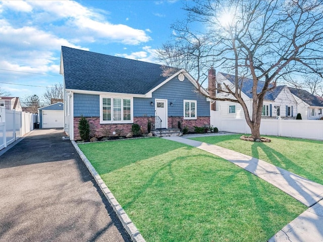 view of front of property with a garage, roof with shingles, an outbuilding, fence, and a front yard