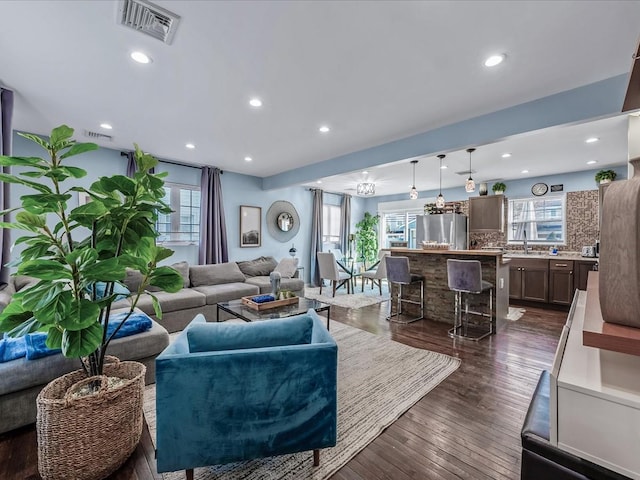 living area with dark wood-style floors, a wealth of natural light, and visible vents