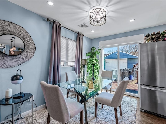 dining space with baseboards, wood finished floors, visible vents, and a healthy amount of sunlight