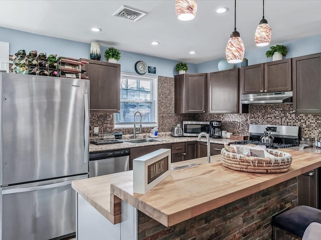 kitchen with stainless steel appliances, visible vents, a sink, butcher block countertops, and under cabinet range hood