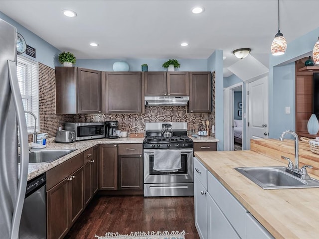 kitchen with dark wood-style floors, appliances with stainless steel finishes, a sink, dark brown cabinetry, and under cabinet range hood