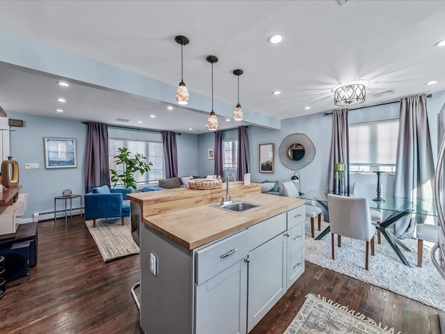 kitchen with dark wood finished floors, a baseboard radiator, butcher block countertops, open floor plan, and a sink