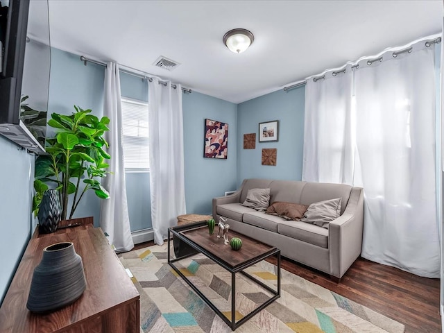 living area with baseboard heating, wood finished floors, and visible vents