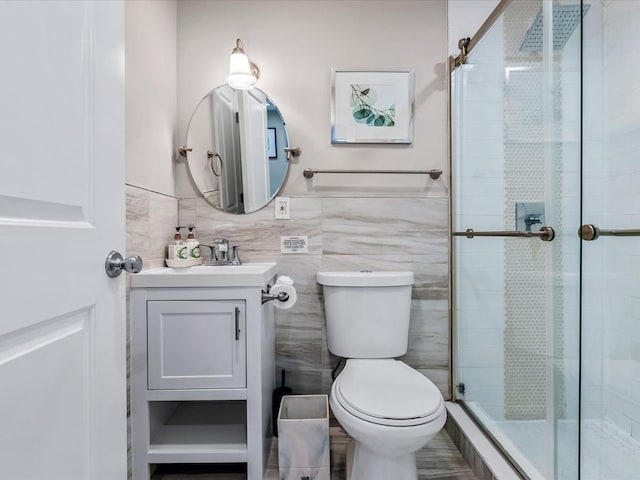 full bath featuring a stall shower, tile walls, vanity, and toilet