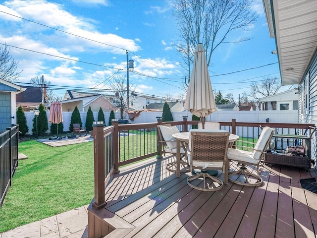 deck featuring outdoor dining area, a fenced backyard, and a lawn