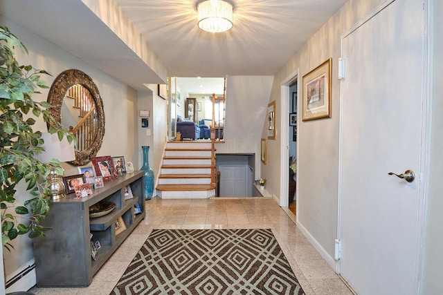 foyer entrance featuring baseboards, stairway, baseboard heating, and a notable chandelier