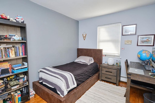 bedroom with a baseboard radiator and wood finished floors