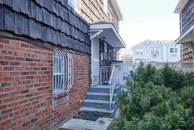 view of side of property featuring brick siding and fence