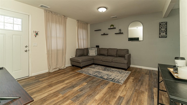 living room featuring visible vents, baseboards, and wood finished floors