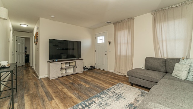 living area with baseboards, visible vents, and dark wood-style flooring