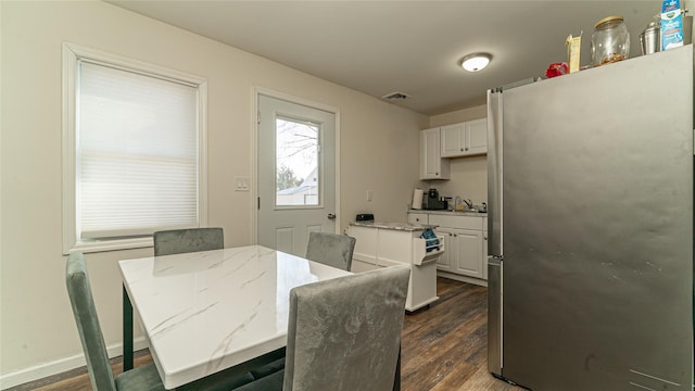 dining room with dark wood finished floors, visible vents, and baseboards