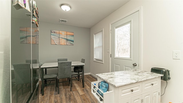 dining area featuring dark wood-type flooring, visible vents, and baseboards