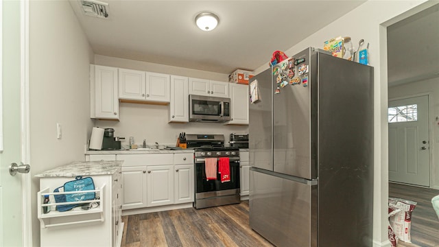 kitchen featuring dark wood-style flooring, a sink, visible vents, light countertops, and appliances with stainless steel finishes