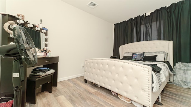 bedroom with lofted ceiling, wood finished floors, visible vents, and baseboards