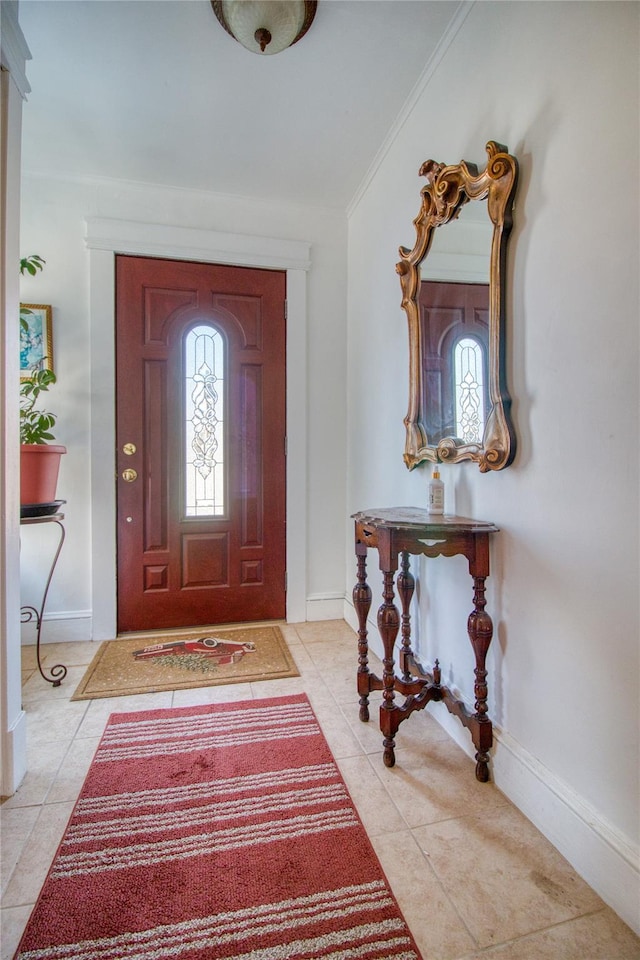 foyer featuring light tile patterned floors, baseboards, and ornamental molding