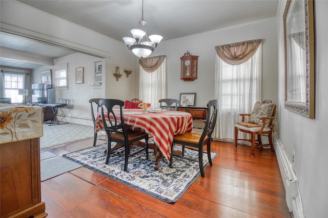 dining area with an inviting chandelier, ornamental molding, and wood finished floors