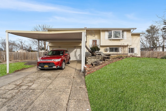 bi-level home with driveway, fence, a front lawn, and a carport