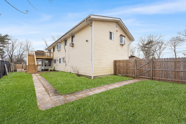 rear view of house featuring a fenced backyard, a yard, a wooden deck, and stairs