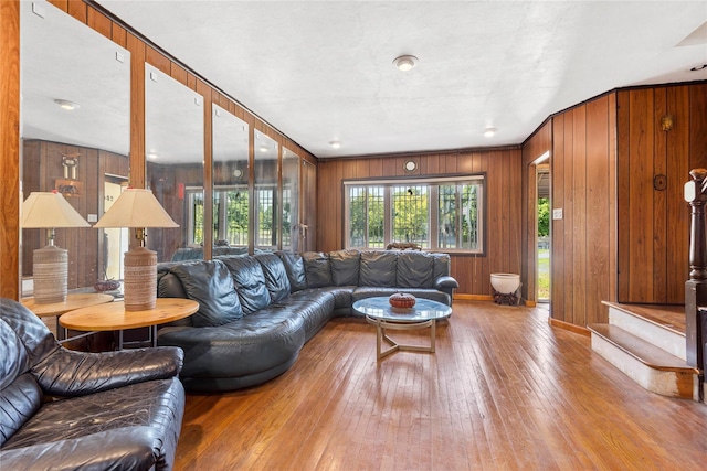 living area with baseboards, wood walls, wood-type flooring, and a healthy amount of sunlight