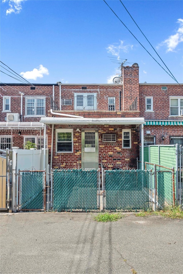 view of property featuring a fenced front yard, a gate, and brick siding