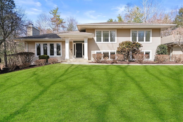 rear view of house featuring a shingled roof, a yard, and a chimney