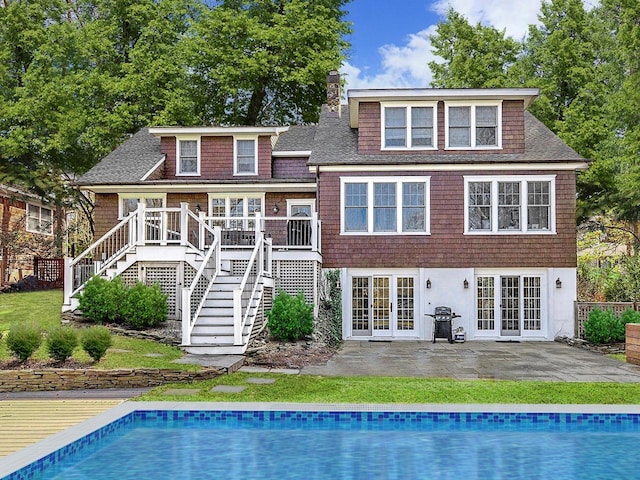 back of house featuring an outdoor pool, a chimney, stairway, french doors, and a patio area