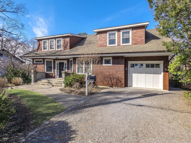 view of front of property featuring an attached garage, driveway, and a shingled roof