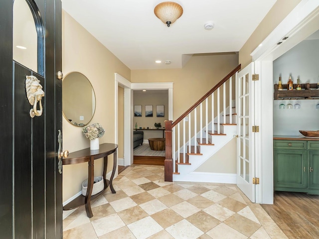 foyer entrance featuring stairs and baseboards