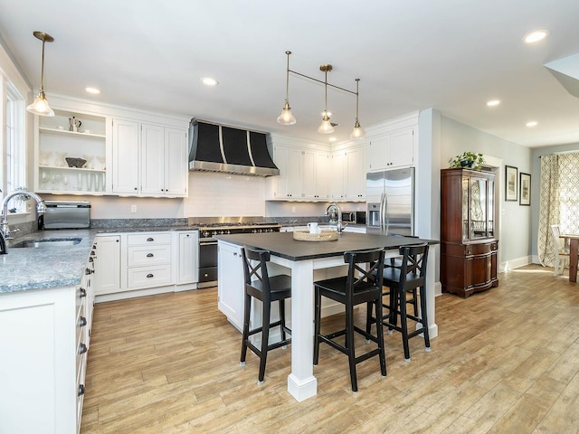 kitchen with appliances with stainless steel finishes, a sink, light wood finished floors, and custom exhaust hood