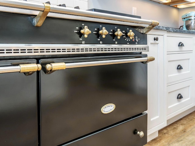 room details featuring light wood-type flooring, range, and white cabinetry