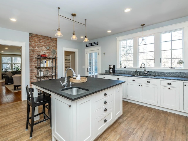 kitchen featuring light wood-style floors, white cabinets, and a sink