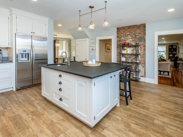 kitchen featuring built in fridge, dark countertops, light wood-style floors, white cabinets, and a sink