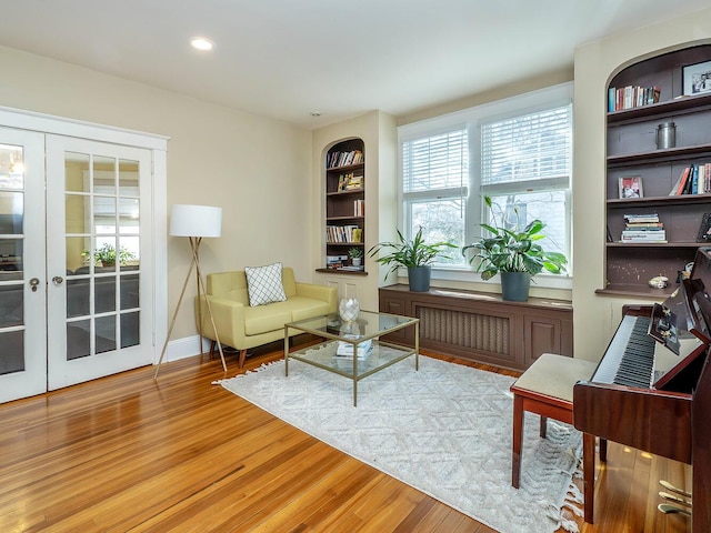 living area with built in shelves, recessed lighting, wood finished floors, baseboards, and french doors