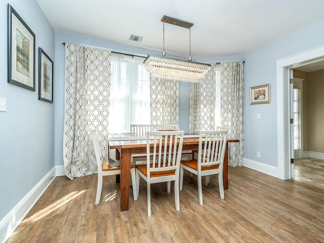 dining room featuring visible vents, baseboards, baseboard heating, and wood finished floors