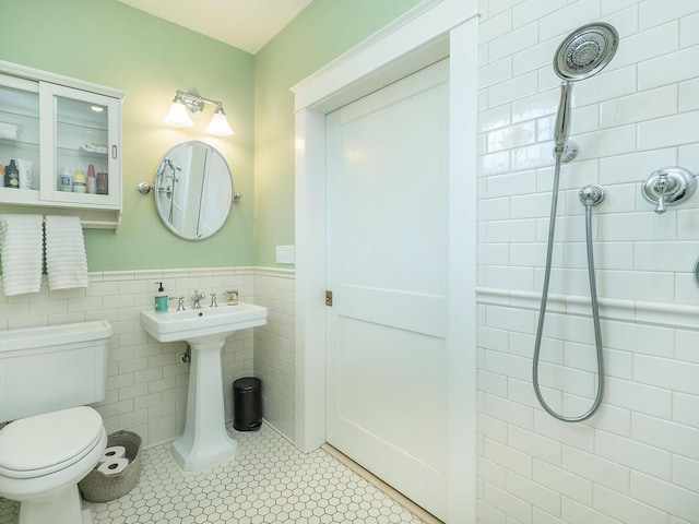 full bathroom featuring a wainscoted wall, tiled shower, tile walls, and toilet