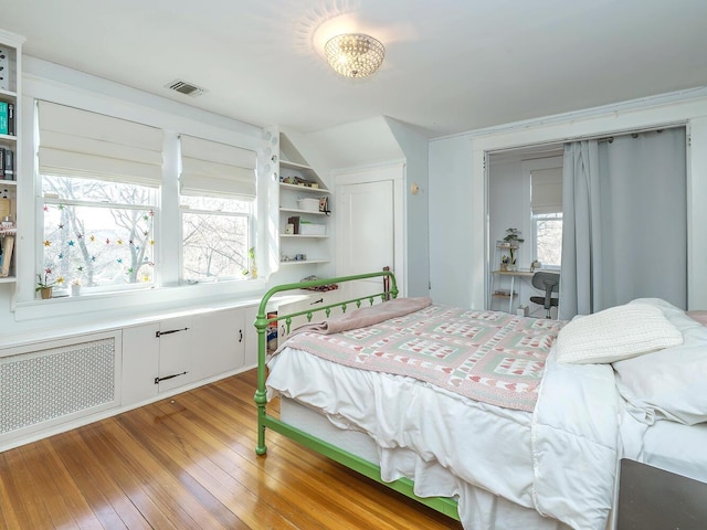 bedroom featuring visible vents, multiple windows, light wood finished floors, and radiator heating unit