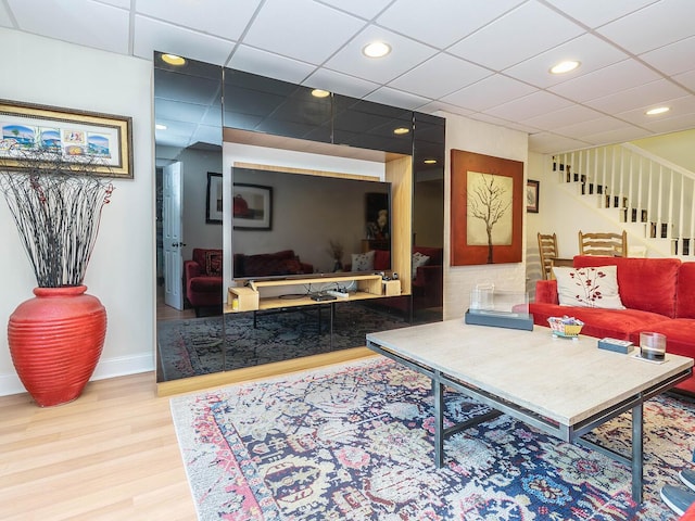 living room with a paneled ceiling, recessed lighting, wood finished floors, baseboards, and stairs