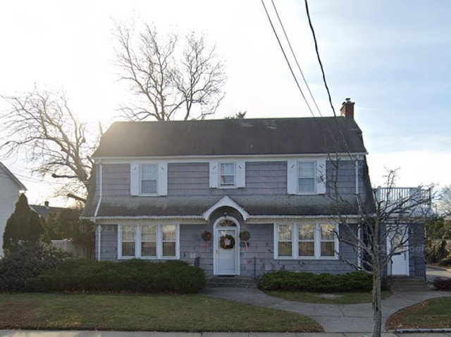 view of front of house featuring a chimney and a front lawn